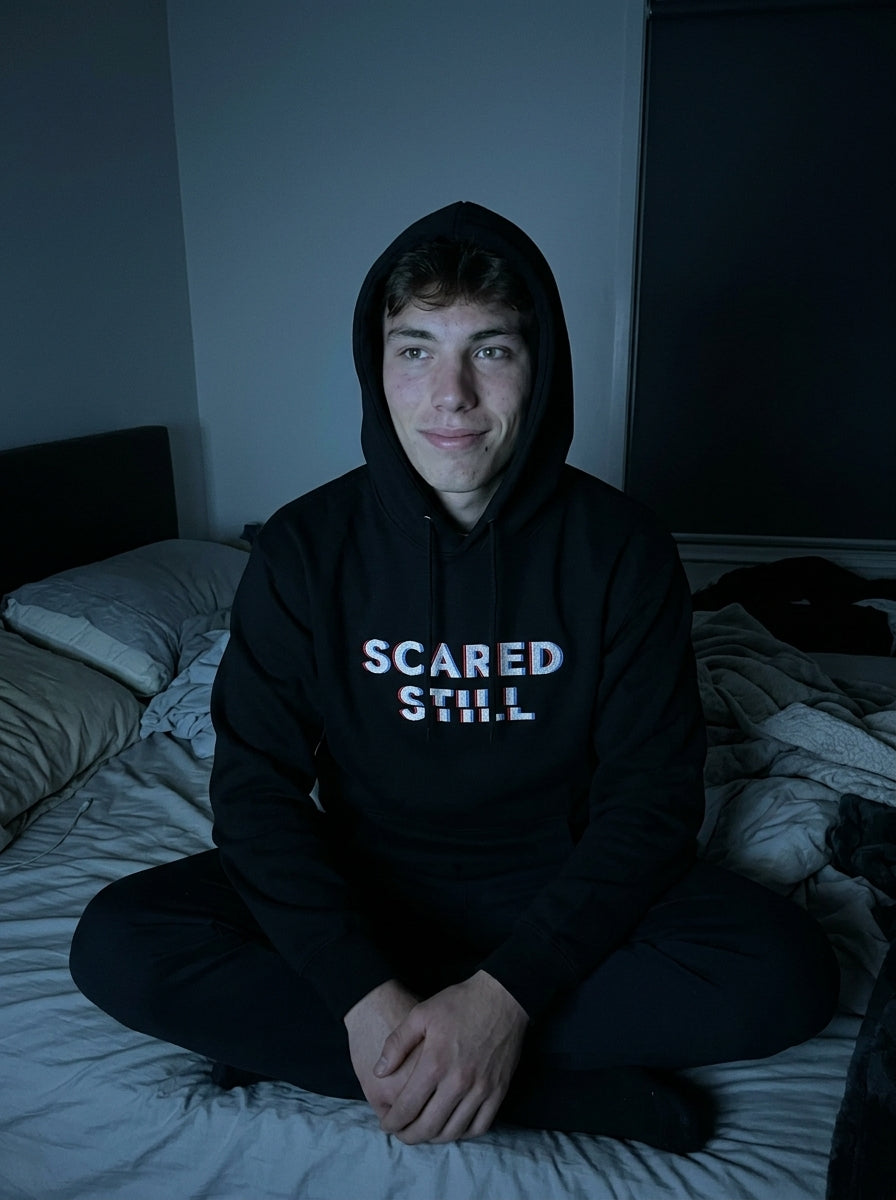 Kevin in the SCARED STILL hoodie, hood up, in a dark bedroom