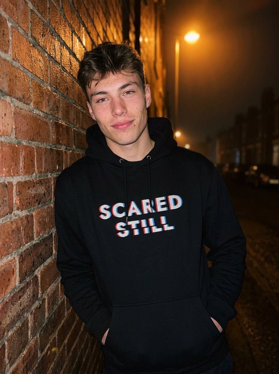 Kevin wearing the SCARED STILL hoodie on a wet street at night